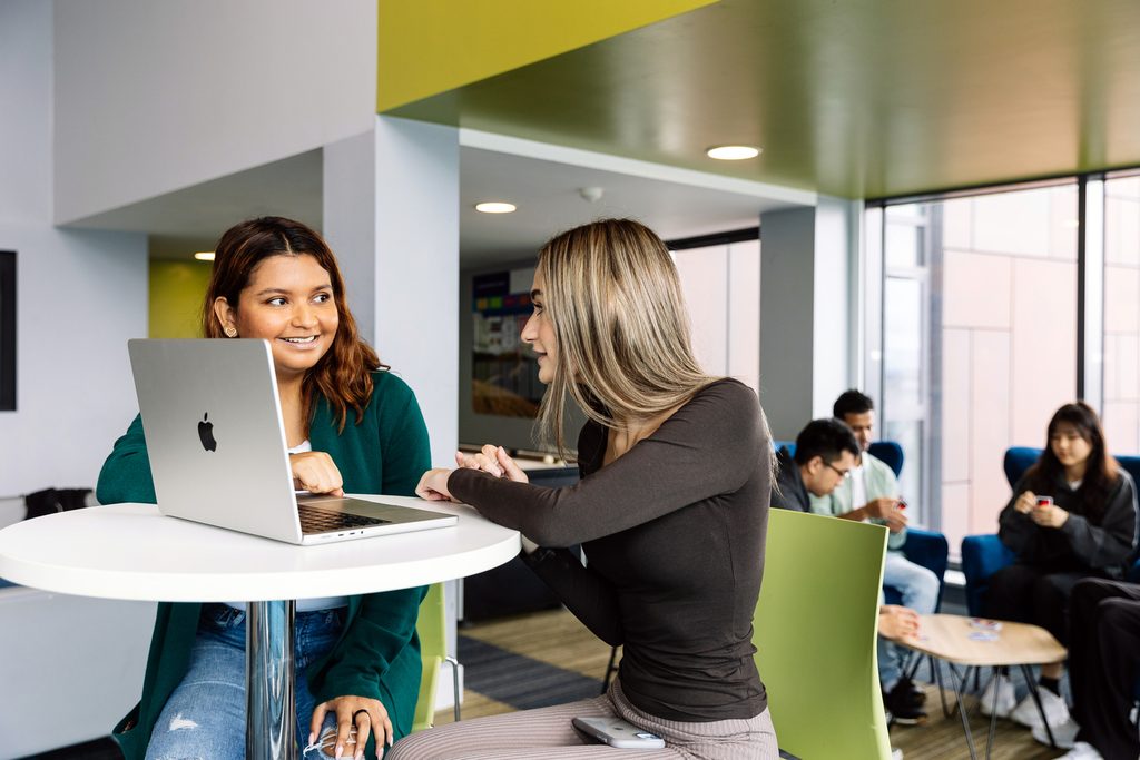 Students chatting in front of a laptop